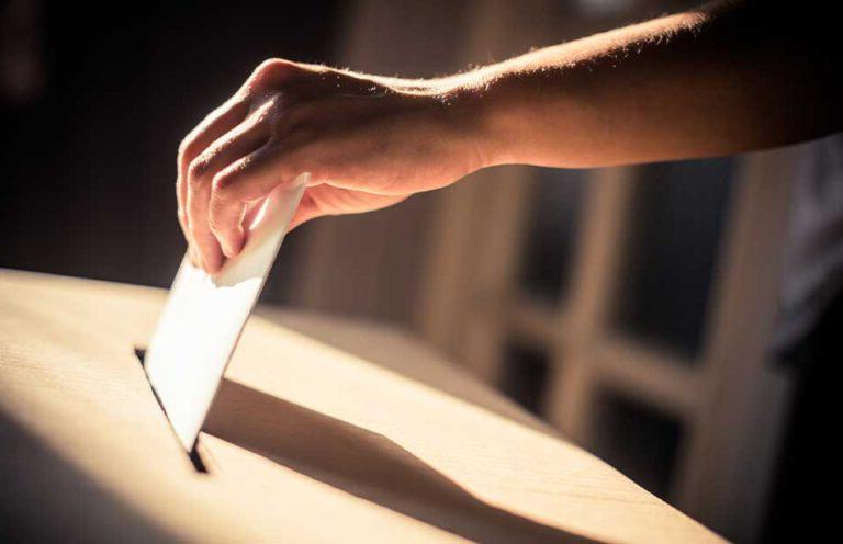 an image of a person putting a voting ballot into a ballot collection box